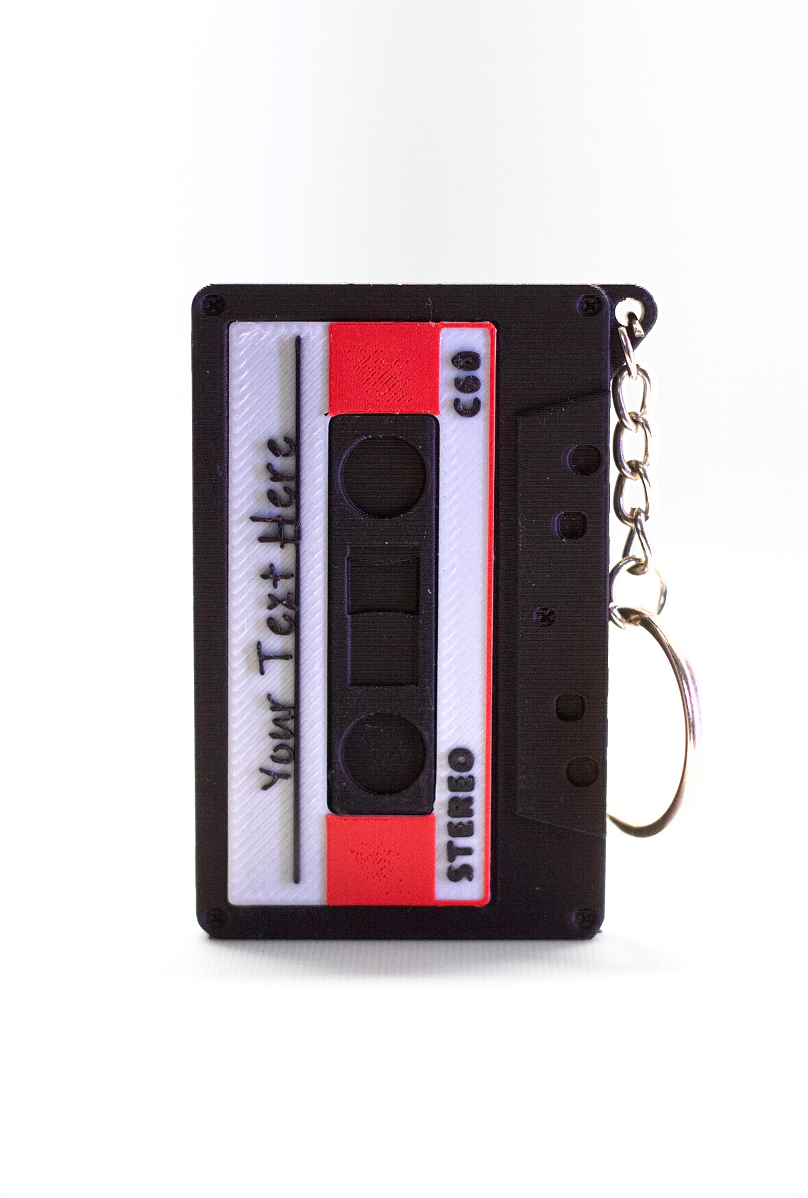 Image of a black cassette keychain with a white and red label, with the text reading "Your Text Here" on the label